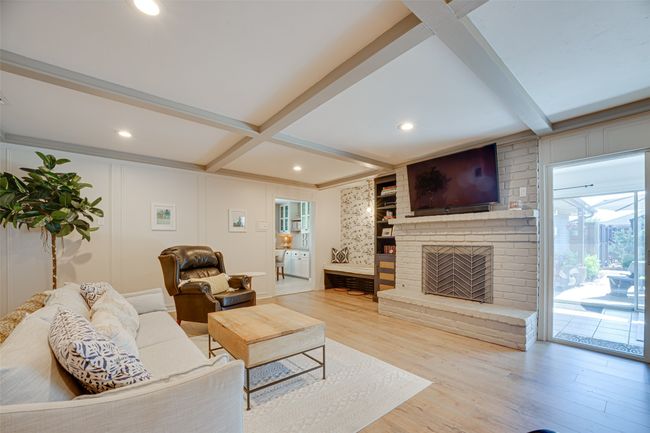 Living room with beamed ceiling, wood finished floors, a brick fireplace, recessed lighting, and a decorative wall | Image 11