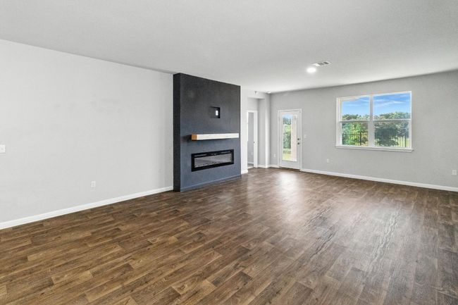 Unfurnished living room with dark wood-style flooring and a large fireplace | Image 9