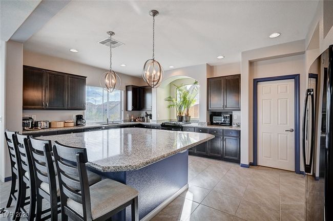 Kitchen featuring Dark Brown Cabinets, a Kitchen Island & Breakfast Bar | Image 17