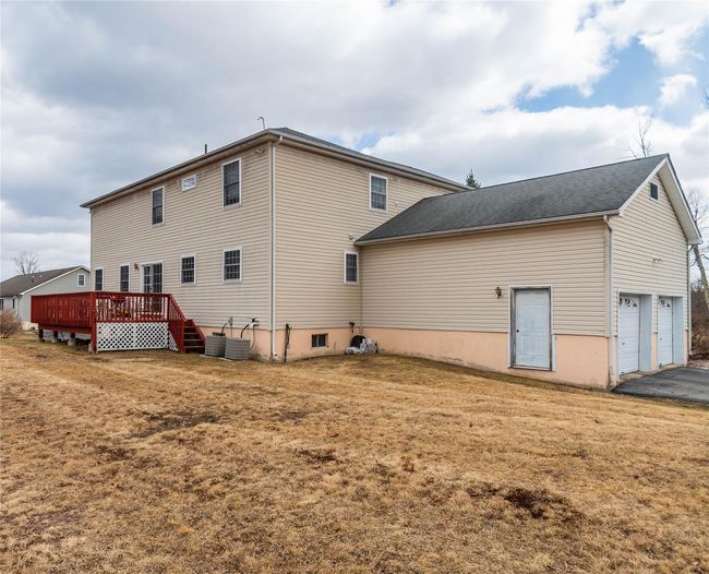Back of house with a lawn, a deck, driveway, cooling unit, and a garage | Image 4