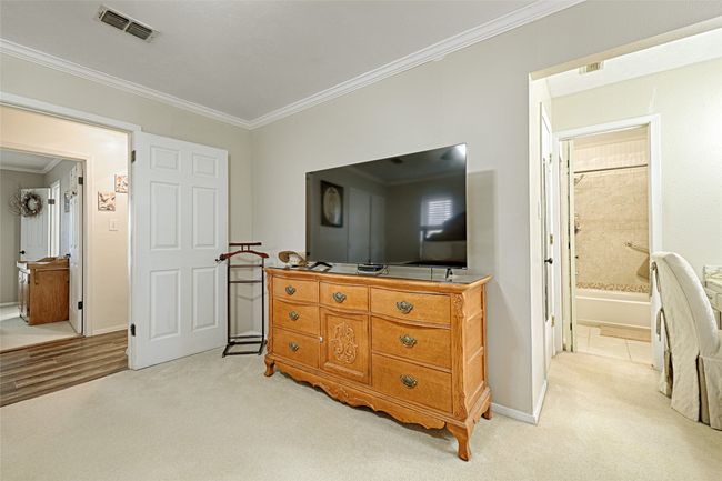Bedroom with light carpet, connected bathroom, and ornamental molding | Image 25