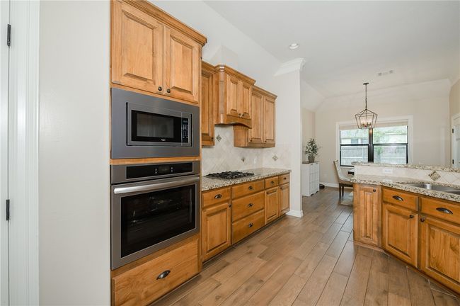Kitchen with light wood finished floors, a sink, stainless steel appliances, and decorative backsplash | Image 12