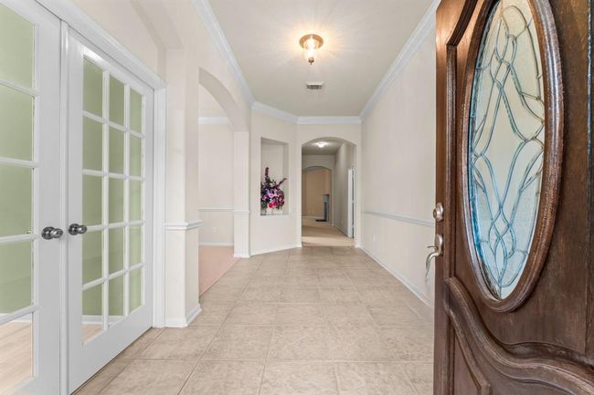 A warm and welcoming entry sets the tone with lovely tile flooring, elegant crown molding, and arched doorways. Just off the foyer, French doors open to a spacious study—ideal for working from home or creating a quiet retreat. | Image 6