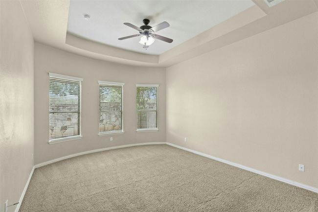 Carpeted spare room with ceiling fan, baseboards, healthy amount of natural light, and a tray ceiling | Image 14
