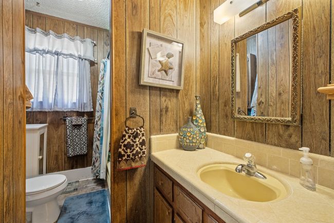 Full bathroom featuring wooden walls, toilet, vanity, and a textured ceiling | Image 13
