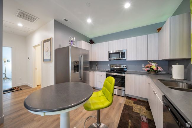 Kitchen with appliances with stainless steel finishes, light wood finished floors, modern cabinets, dark countertops, and recessed lighting | Image 8