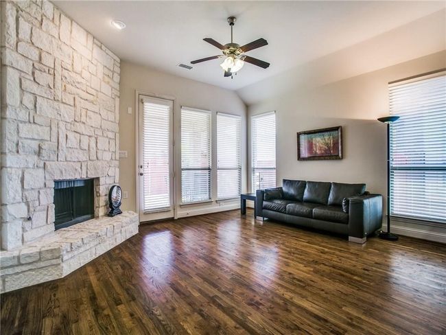 Living area featuring ceiling fan, wood finished floors, a fireplace, baseboards, and vaulted ceiling | Image 10