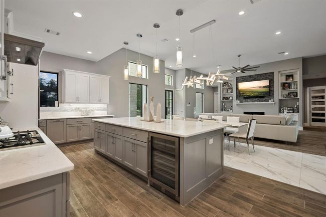 The kitchen features a sleek gas stovetop, a dedicated wine refrigerator, and a convenient double sink, combining style and functionality for a superior cooking experience. | Image 17