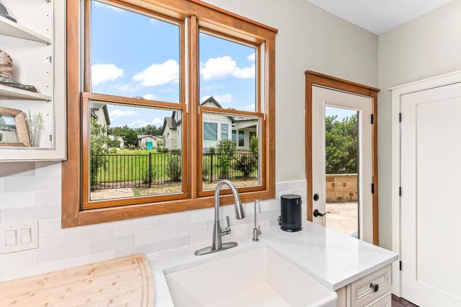Kitchen with a sink, light countertops, backsplash, and white cabinetry | Image 9