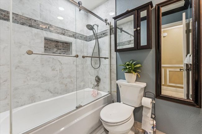 Bathroom featuring toilet, a textured wall, and enclosed tub / shower combo | Image 8