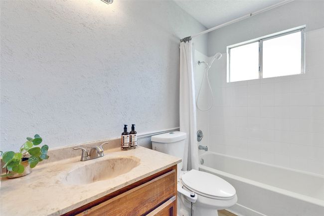 Bathroom with shower / bath combination with curtain, a textured wall, and vanity | Image 26