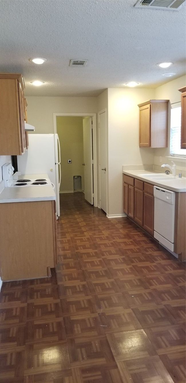 Kitchen featuring dishwashing machine, a textured ceiling, range, and light countertops | Image 10