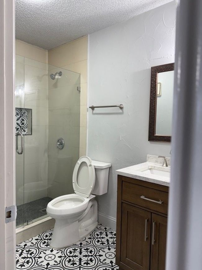 Full bath featuring a textured ceiling, vanity, a stall shower, and tile patterned floors | Image 9