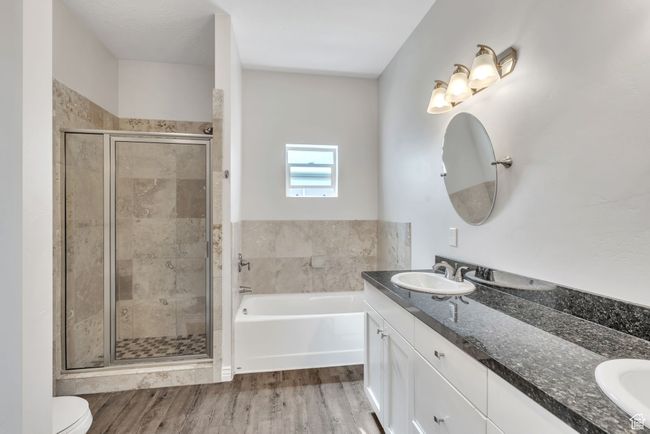 Bathroom with double vanity, a stall shower, a bath, and wood finished floors | Image 19