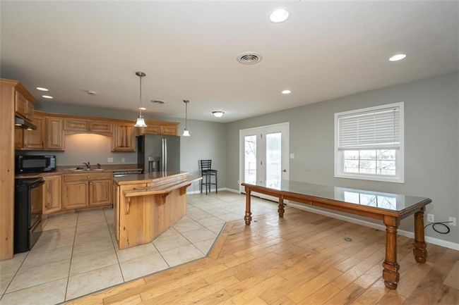 Kitchen with visible vents, black appliances, a sink, a kitchen island, and light wood finished floors | Image 9