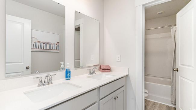 Full bath featuring toilet, double vanity, wood finished floors, and shower / tub combo with curtain | Image 28