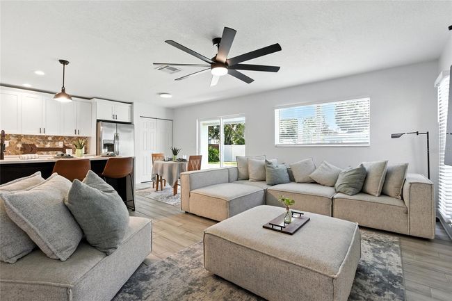 Spacious and inviting, this open-concept living area is ideal for entertaining—anchored by a bold black brick fireplace and oversized ceiling fan for added style and comfort. | Image 4