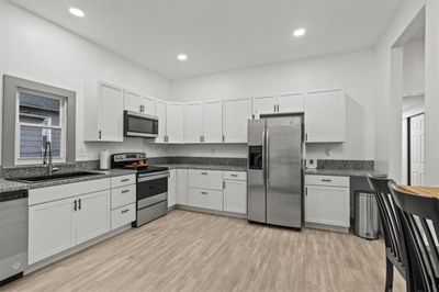 Kitchen with white cabinets, sink, appliances with stainless steel finishes, and light hardwood / wood-style flooring | Image 2