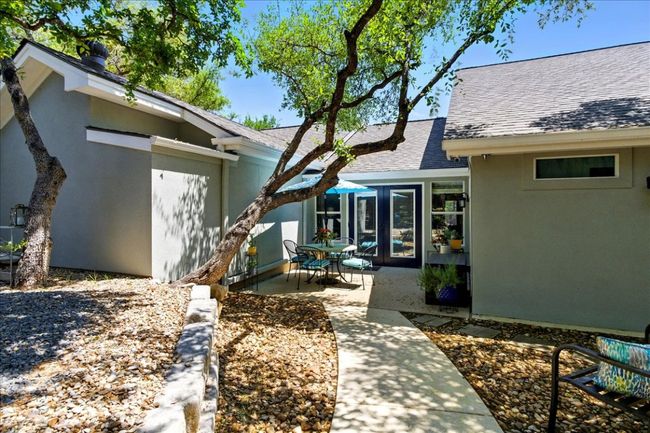 Doorway to property with roof with shingles, a patio, and stucco siding | Image 4