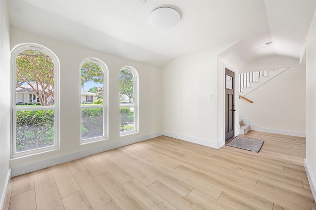 Unfurnished living room with healthy amount of natural light, vaulted ceiling, light wood finished floors, and stairway | Image 28