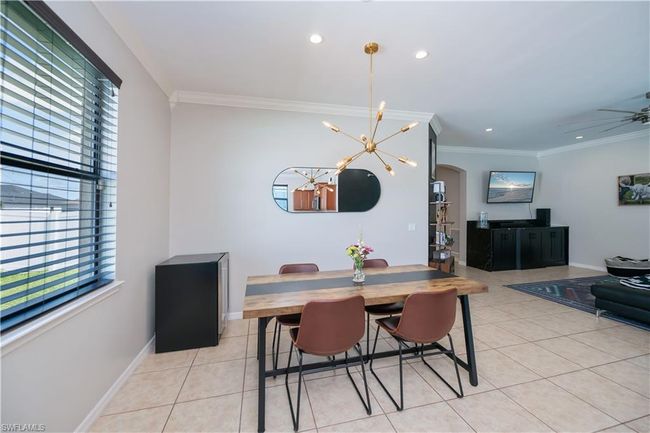 Dining area with a healthy amount of sunlight, arched walkways, light tile patterned floors, and crown molding | Image 11