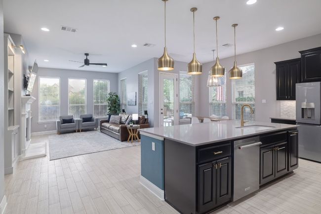 Kitchen with appliances with stainless steel finishes, a sink, ceiling fan, a kitchen island with sink, and light countertops | Image 11
