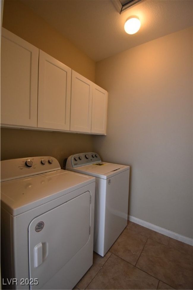 Laundry room with cabinet space, washing machine and clothes dryer, baseboards, and light tile patterned floors | Image 19