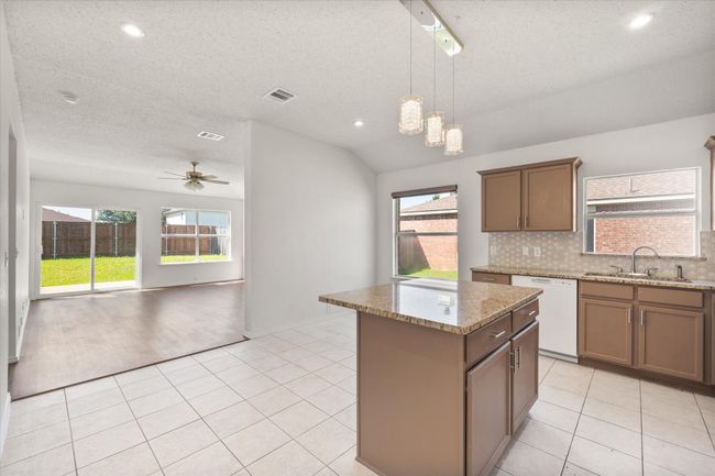Kitchen featuring white dishwasher, a sink, a center island, healthy amount of natural light, and recessed lighting | Image 6