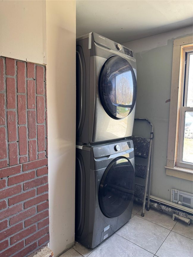 Laundry room featuring visible vents, stacked washer / dryer, tile patterned floors, and laundry area | Image 15