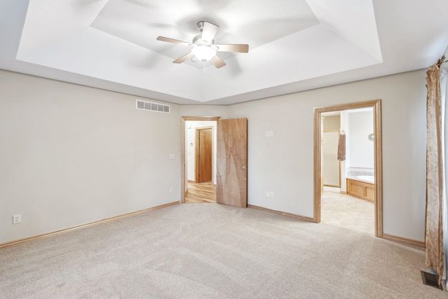 Unfurnished bedroom with a raised ceiling, light colored carpet, baseboards, and ensuite bathroom | Image 11