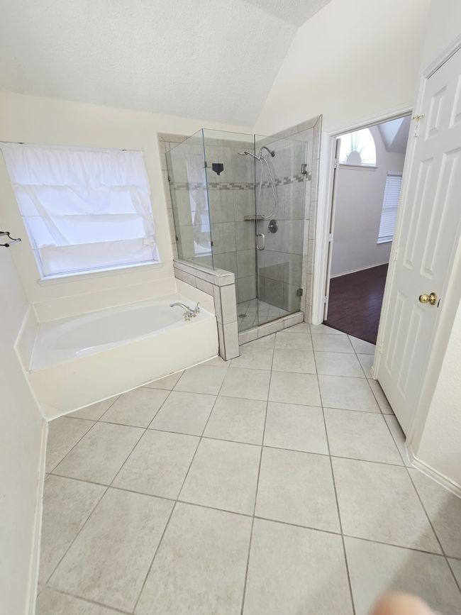 Bathroom featuring vaulted ceiling, tile patterned floors, a shower stall, a garden tub, and a textured ceiling | Image 5