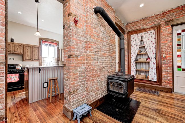 interior space with brick wall, a wood stove, wood-type flooring, and recessed lighting | Image 25