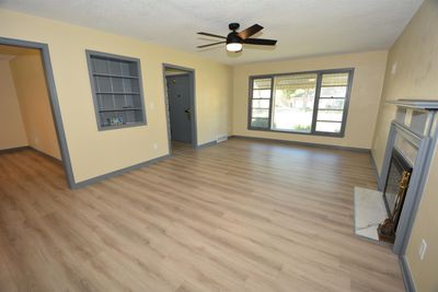 Unfurnished living room featuring built in shelves, a textured ceiling, light hardwood / wood-style flooring, and a premium fireplace | Image 2