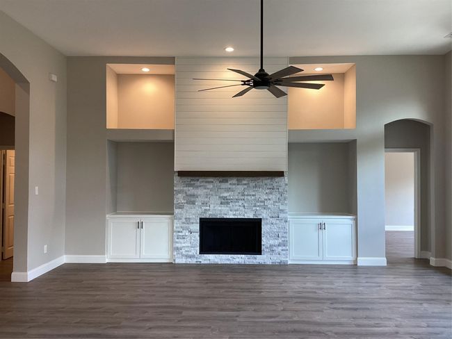Unfurnished living room featuring arched walkways, built in features, ceiling fan, dark wood-style floors, and recessed lighting | Image 15