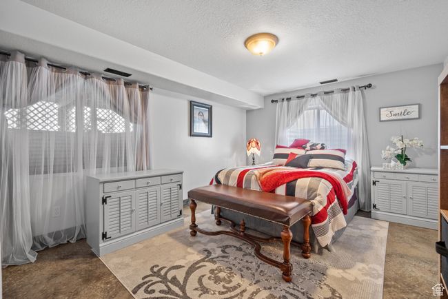 Bedroom featuring visible vents, finished concrete floors, and a textured ceiling | Image 26