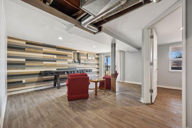 The lower level features vinyl flooring, a walkout sliding door toward the lake, recessed lighting, and a stylish accent wall. | Image 12