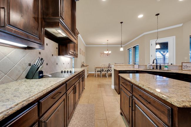 Kitchen with a sink, ornamental molding, tasteful backsplash, a chandelier, and black electric stovetop | Image 7