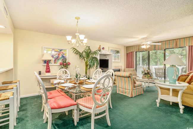 Dining room with carpet, a chandelier, a textured ceiling, and a ceiling fan | Image 5