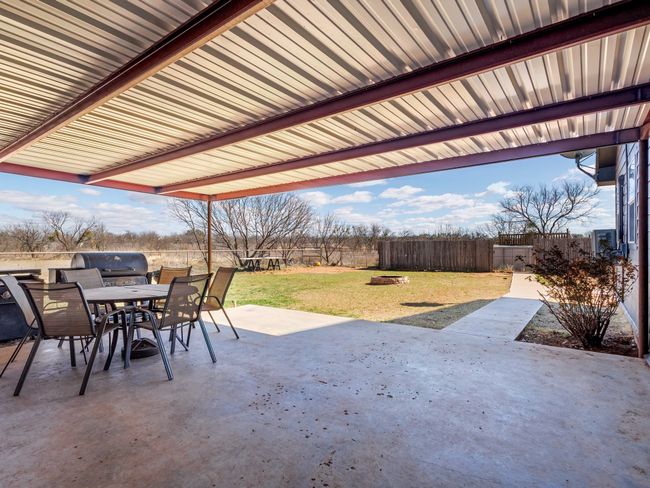 Back covered patio looks out towards above ground pool and animal pens just beyond the fenced pool area. | Image 32