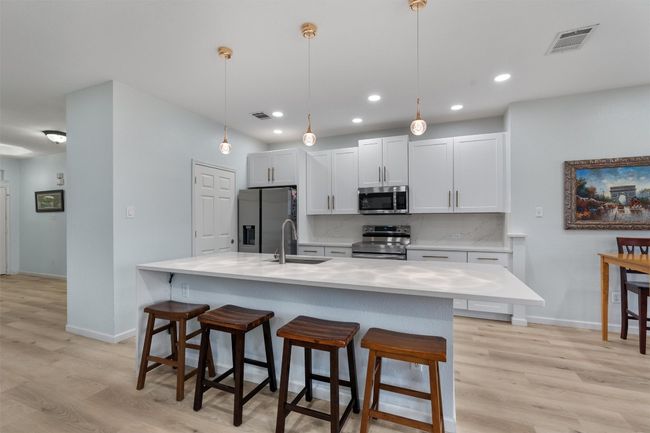 Tastefully updated kitchen featuring stainless steel appliances, light countertops, and large a breakfast bar adding to extensive counter space | Image 11