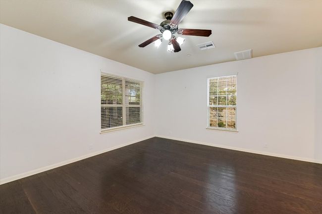 Spare room with dark wood-type flooring, healthy amount of natural light, and a ceiling fan | Image 4