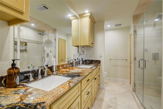 The primary en-suite bathroomboasts stunning granite counterswith dual sinks, added built-insfor extra storage, and anoversized shower with beautifultile accents complete with insetniche for shampoos and soaps.The oversized walk-in shower is a great amenity for the ensuite bathroom. | Image 21