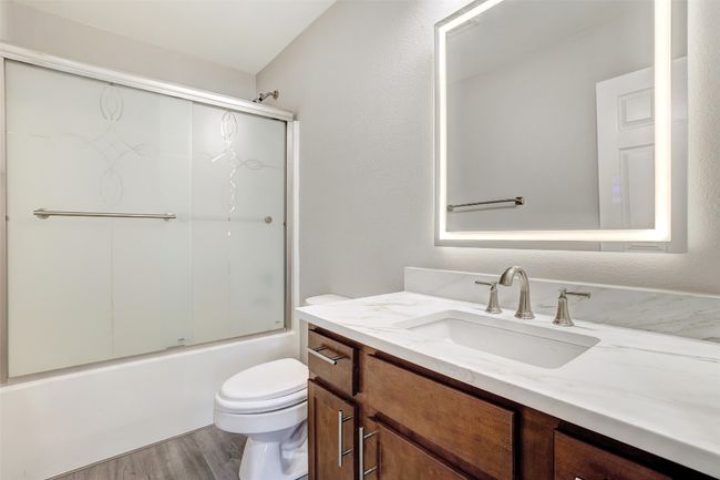 Hall Bathroom with vanity, wood finished floors, and shower / bath combination with glass door | Image 25