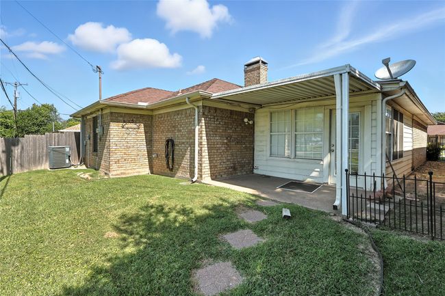 Rear view of property with a chimney, brick siding, roof with shingles, and a patio area | Image 7
