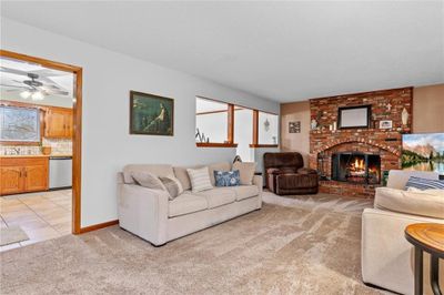 Carpeted living room featuring a fireplace, ceiling fan, and sink | Image 3