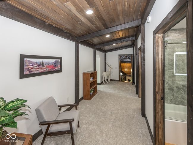 hall featuring wooden ceiling with exposed beams, light carpet, and baseboards | Image 36