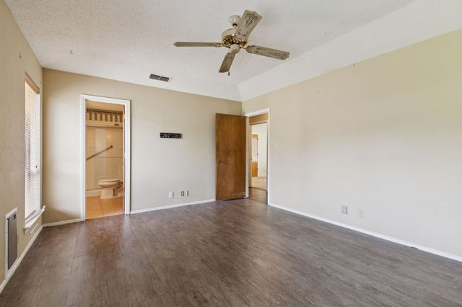 Unfurnished bedroom with wood finished floors, a textured ceiling, ensuite bathroom, and ceiling fan | Image 19