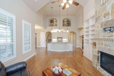 Living room with ceiling fan, a stone fireplace, high vaulted ceiling, and light hardwood / wood-style floors | Image 3