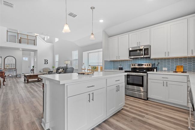 Kitchen with stainless steel appliances, light countertops, light wood-type flooring, white cabinets, and recessed lighting | Image 14