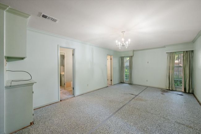 Master bedroom featuring ornamental molding, a chandelier, and ensuite bathroom with french doors leading to back yard. | Image 28